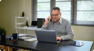 man in front of a laptop holding a phone
